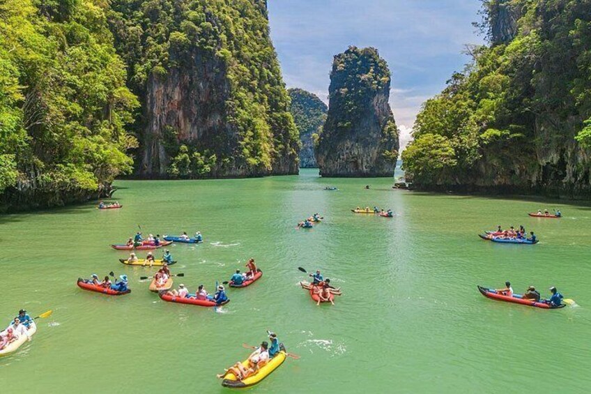 A group of people kayaking on a river surrounded by lush green cliffs. 2