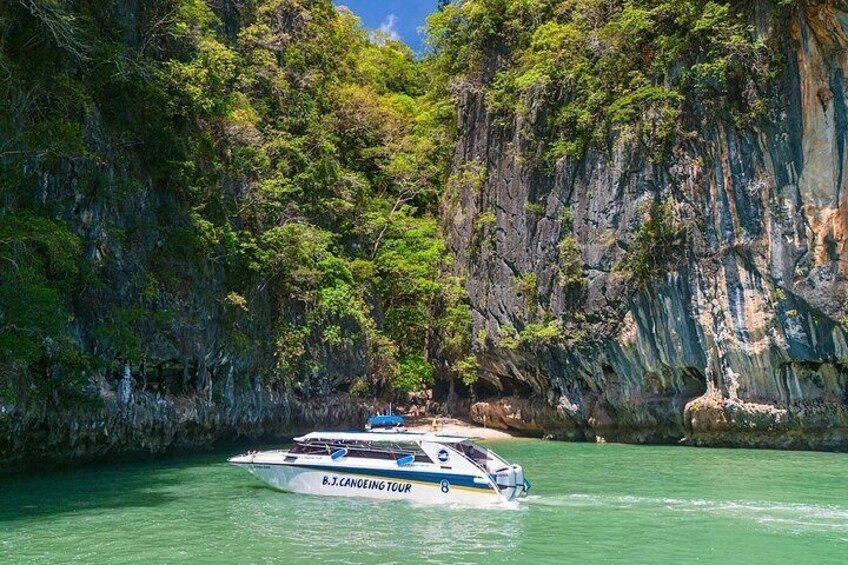 A boat named B.J. CANOEING TOUR on a calm body of water surrounded by lush greenery and rocky cliffs. 3