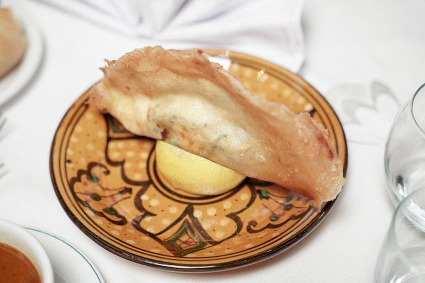 A plate with a piece of fried fish and a lemon wedge. 3