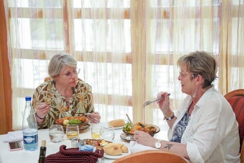Two people dining at a table with various dishes, glasses, and a bottle. 3