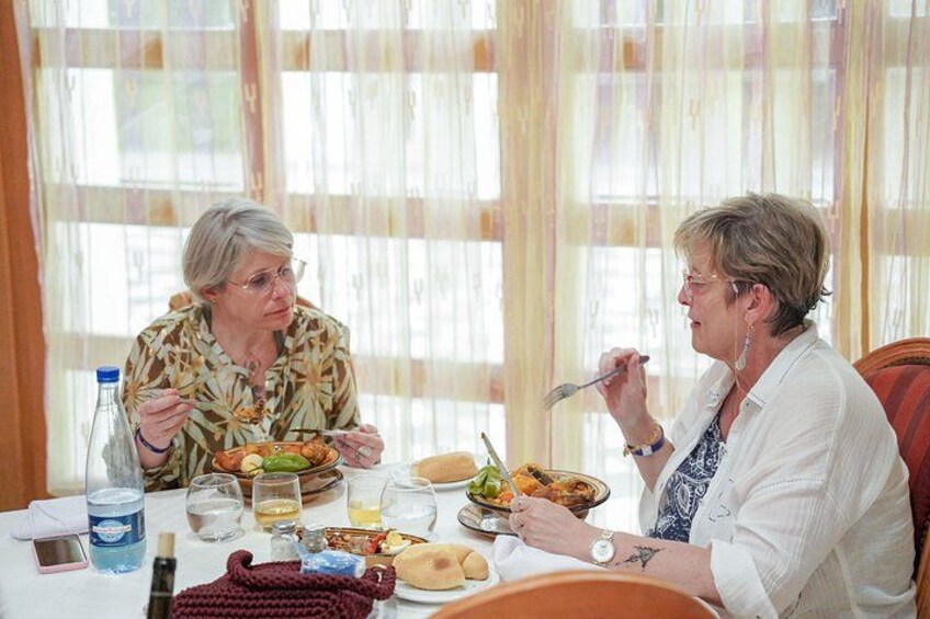 Two people dining at a table with various dishes, a bottle, and glasses. 5