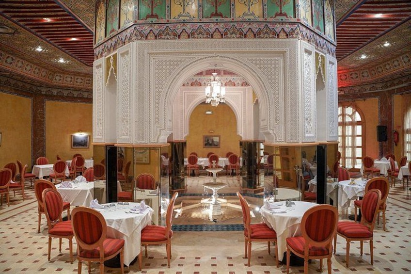 A grand dining hall with ornate arches, red chairs, and tables set for a meal. 5