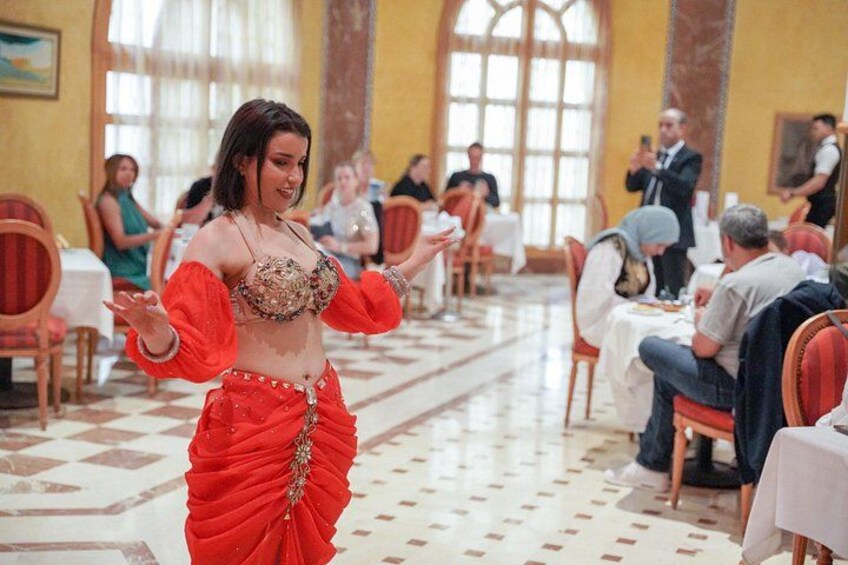 A woman in a red dress dancing in a room with tables and chairs. 3