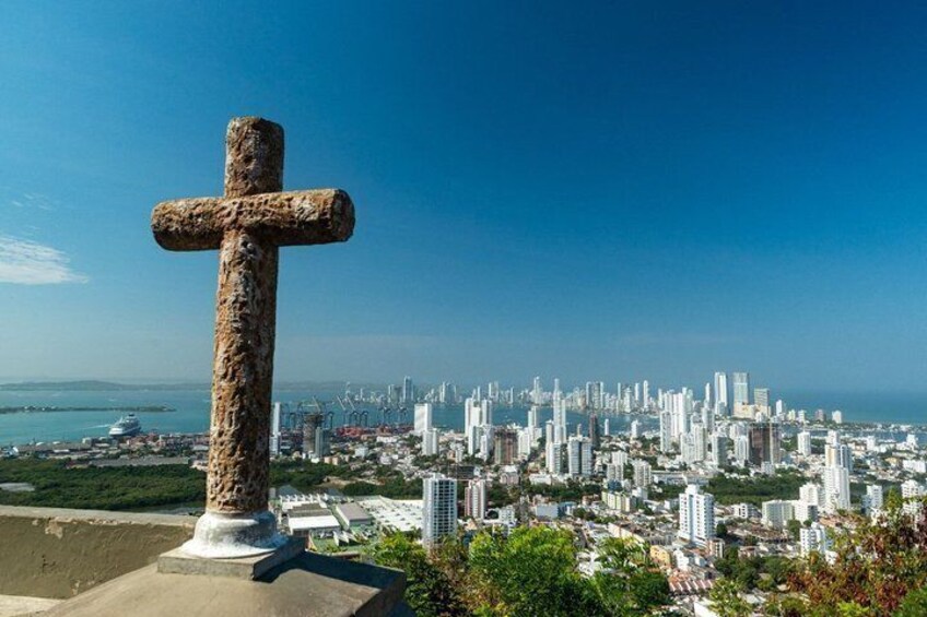 A cross monument with a cityscape in the background. 2