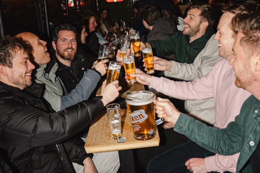 A group of people toasting with beer glasses at a bar. 4
