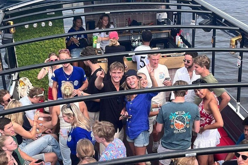 A group of people on a boat with a green wall and a bar area. 2
