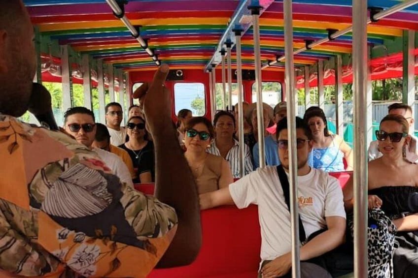 A colorful bus with passengers seated inside. 1