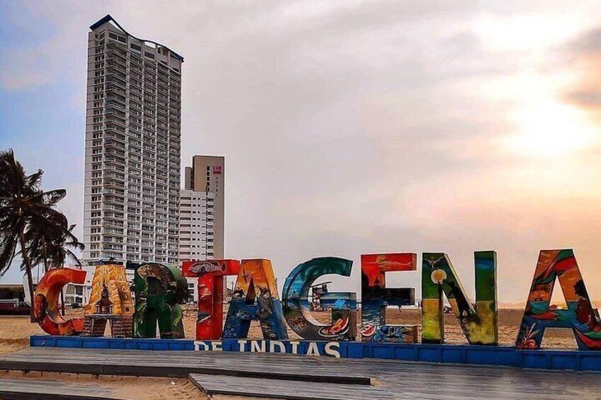 A colorful sign spelling 'CARTAGENA' with a tall building in the background. 3