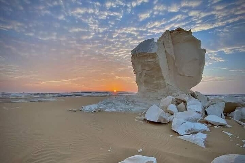 A large rock formation on a beach at sunset. 5