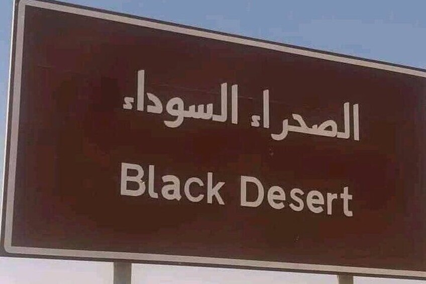 A sign with Arabic text and the English translation "Black Desert". 4