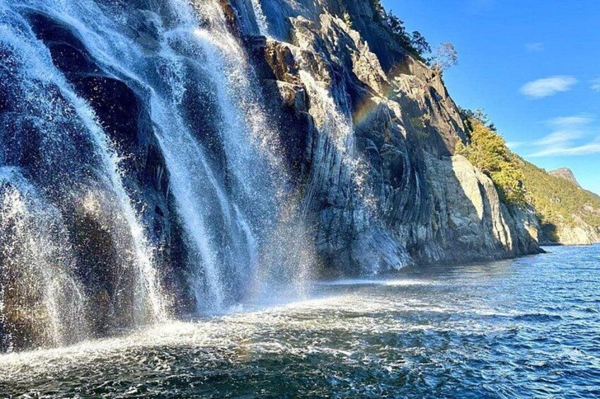 Ein Wasserfall stürzt über eine felsige Klippe in ein Gewässer. 3