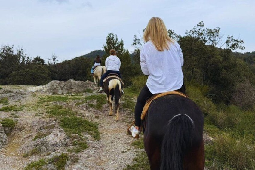 Tres personas montando a caballo por un sendero con montañas al fondo. 5