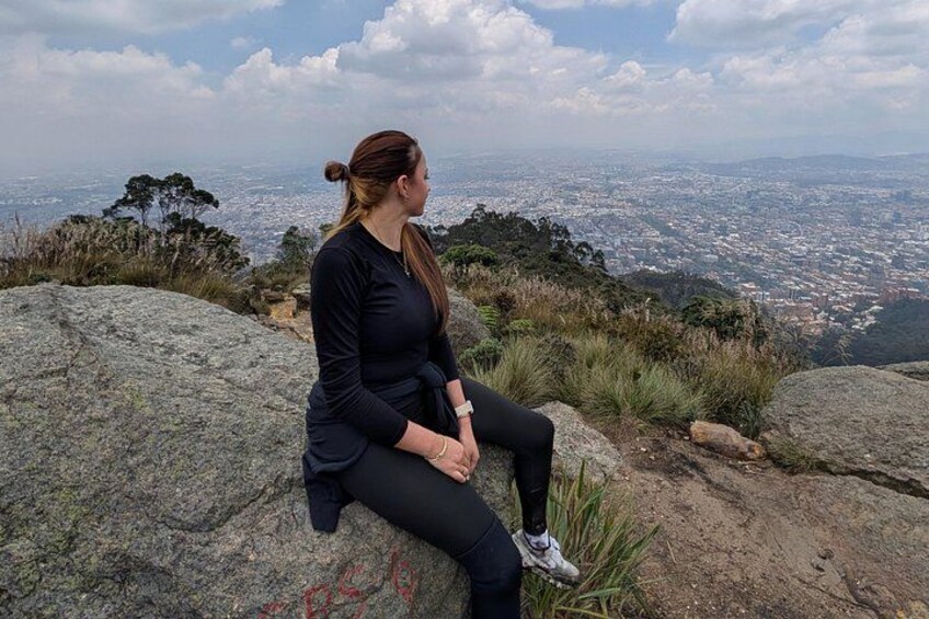 A person sitting on a rock overlooking a cityscape. 5