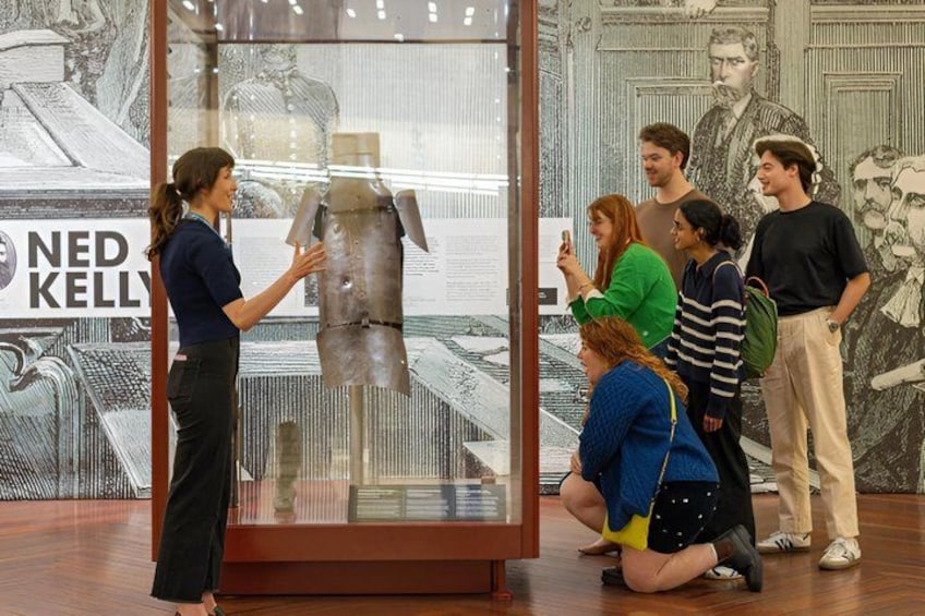 Une exposition dans un musée, avec un mannequin exposé dans une vitrine, entouré de visiteurs. 5