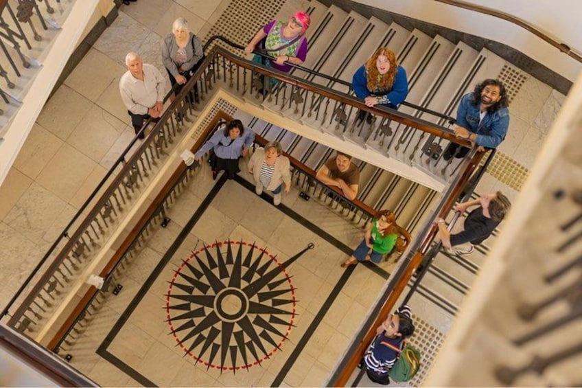 Un motif circulaire au sol, composé d’un point central et de lignes rayonnantes, le tout entouré d’une balustrade. 4