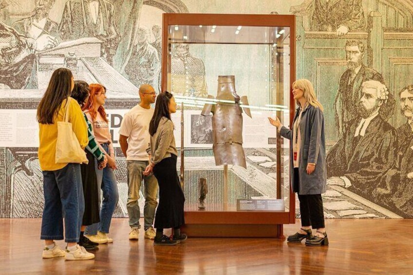 Un groupe de personnes observe une vitrine contenant des sculptures dans un musée d’art. 4