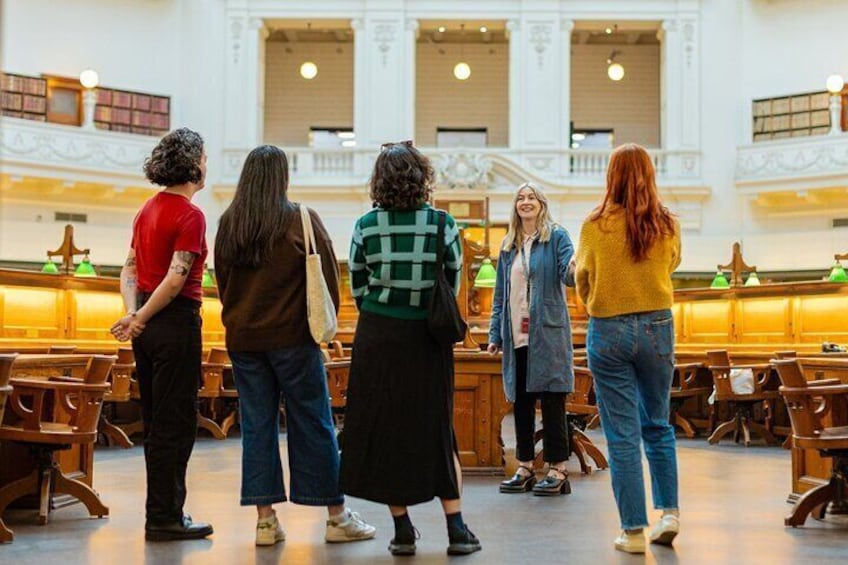 Un groupe de personnes se tient debout dans une église, avec des bancs en bois et un plafond haut. 2