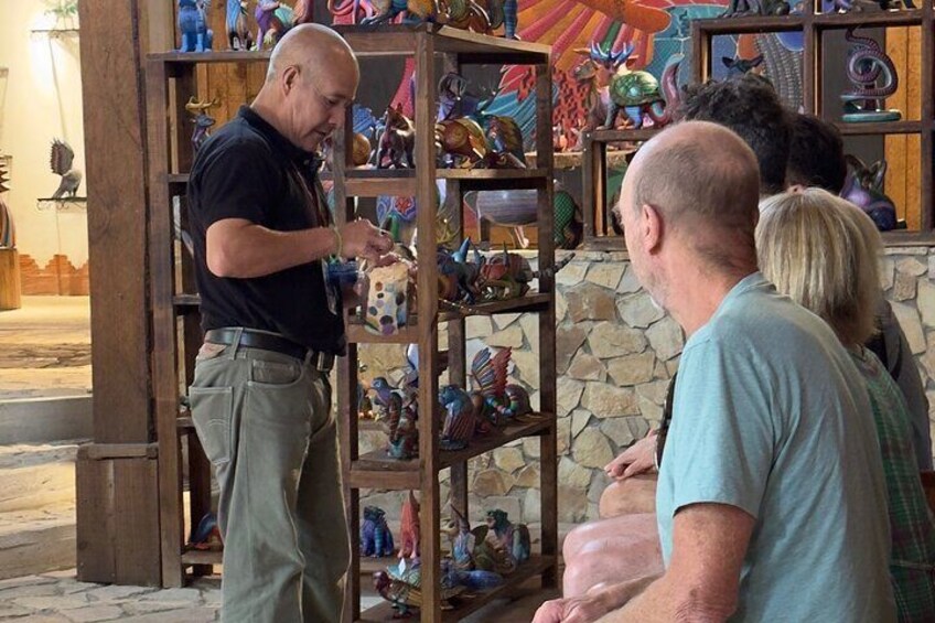 A man examining colorful figurines in a wooden display case. 5