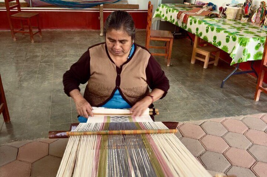 A person weaving on a loom. 3