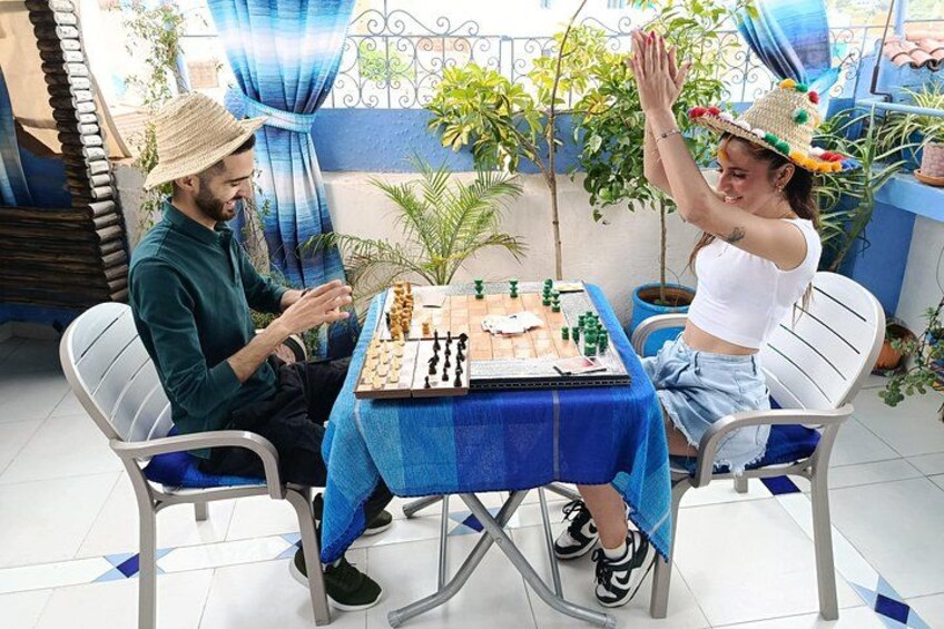 Zwei Personen spielen draußen auf einem Tisch mit blauer Tischdecke Schach. 5