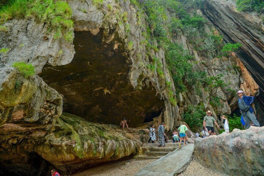 A rocky cave entrance with people climbing and exploring. 4