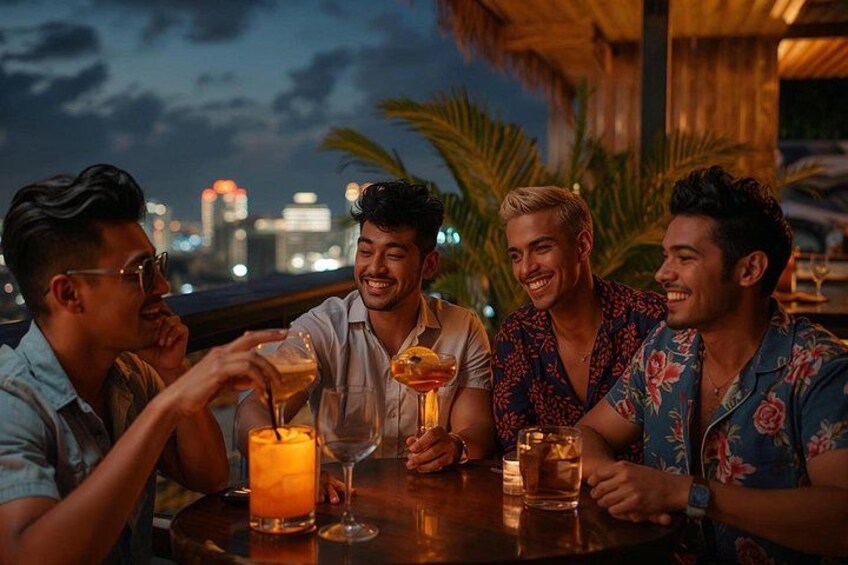 Four people sitting at a table with drinks, palm trees, and a city skyline in the background. 1