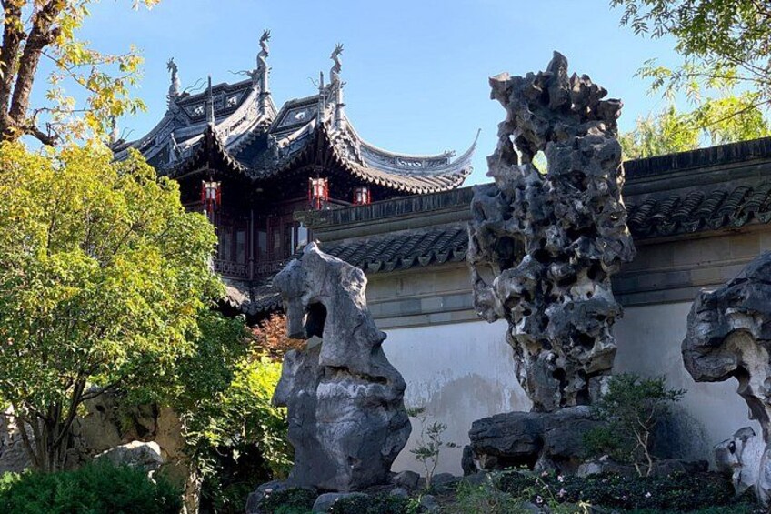 A traditional Chinese building with ornate architecture, surrounded by large rock formations and lush greenery. 1