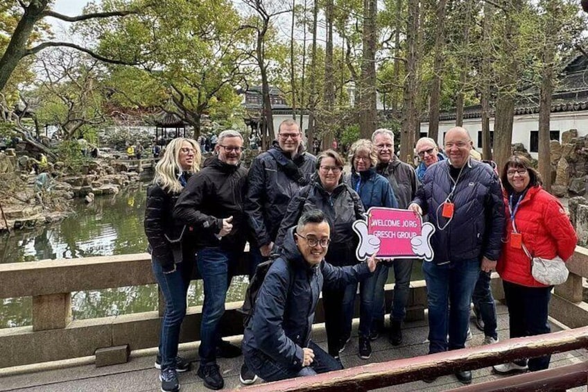 A group of people posing for a photo near a pond with a sign reading 'WELCOME JORIS GRESH GROUP'. 5