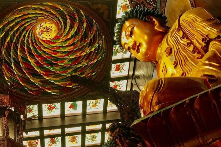 A golden statue of a seated figure with a large, colorful circular object above it. 2