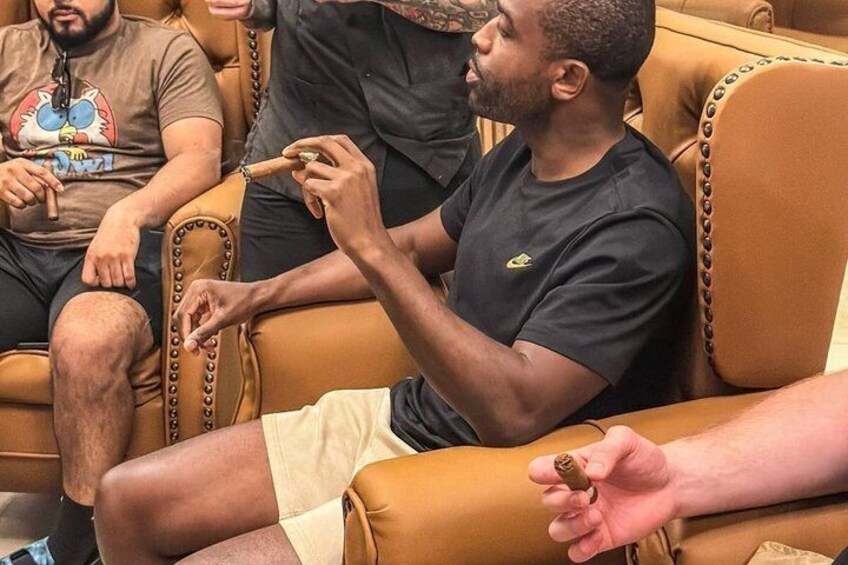 En person sidder på en lædersofa med en cigar. 4