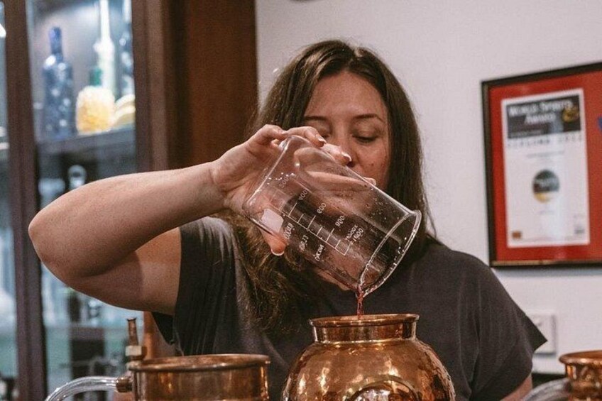 A person pouring a liquid from a measuring cup into a copper pot. 2