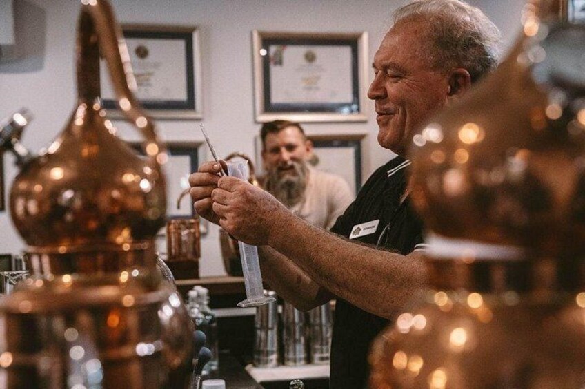 A person holding a thermometer, likely measuring temperature, in a setting with copper vessels and a certificate on the wall. 1