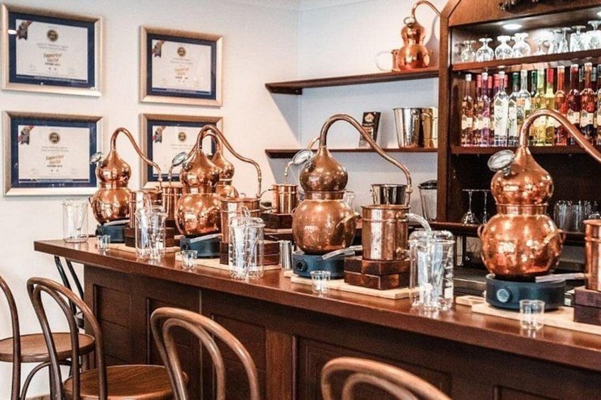 A bar with copper stills, glasses, and shelves of liquor bottles. 5