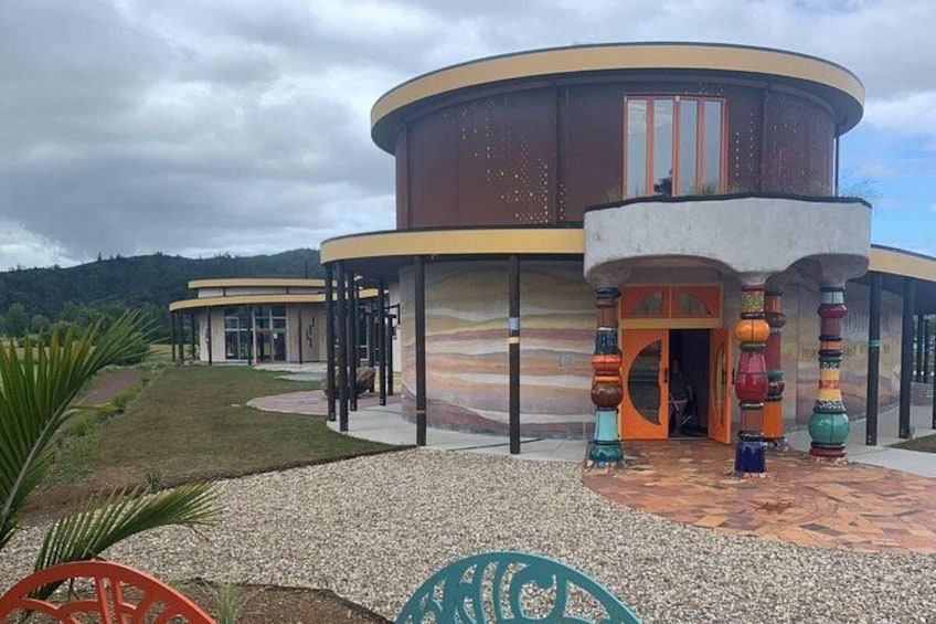 Un edificio moderno con fachada curva, zona de acceso cubierta y coloridas columnas decorativas. 5