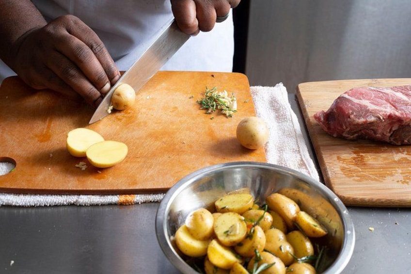 A person chopping potatoes on a cutting board with a knife. 5