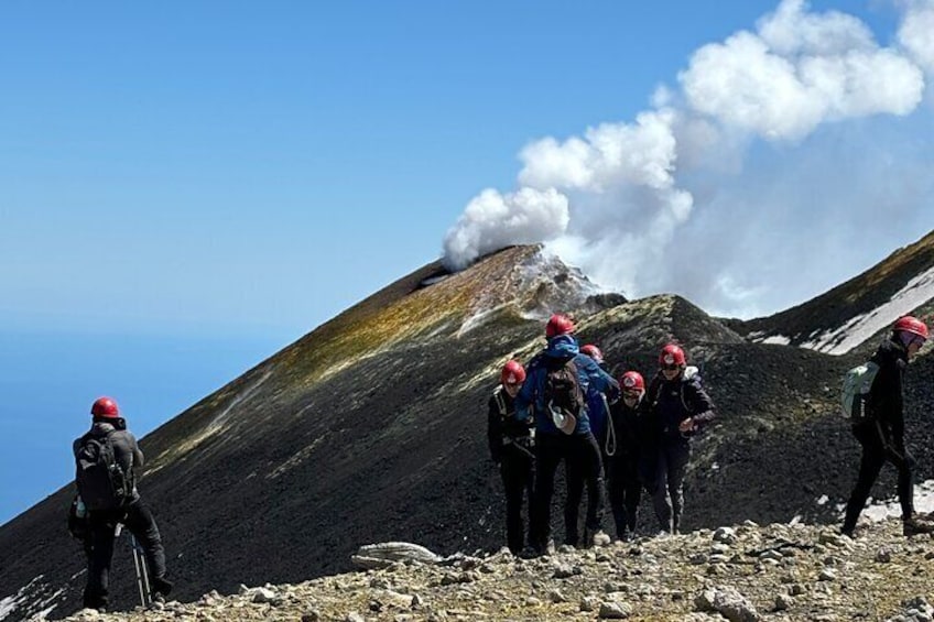 A group of hikers on a rocky mountain with a visible volcanic eruption in the background. 3