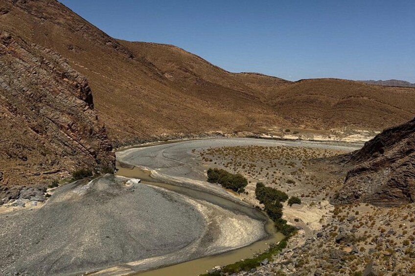 Un río sinuoso en un paisaje desértico con terreno rocoso y vegetación escasa. 2