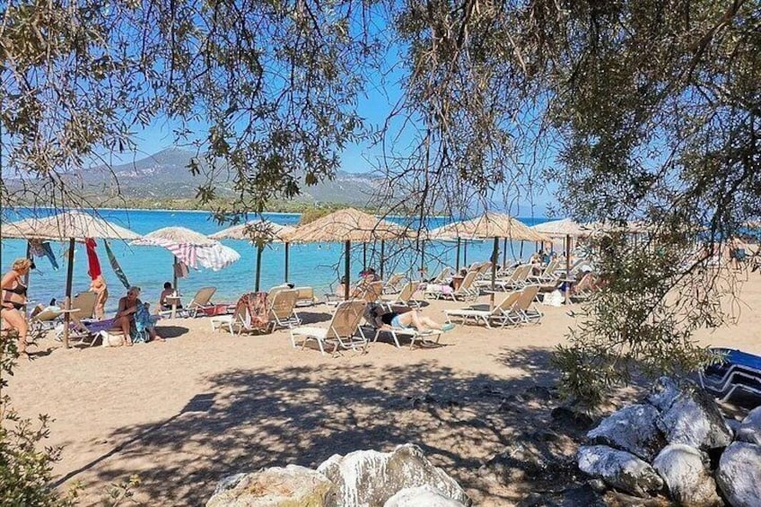 A beach with sun loungers and umbrellas, a clear sky, and a mountainous backdrop. 5