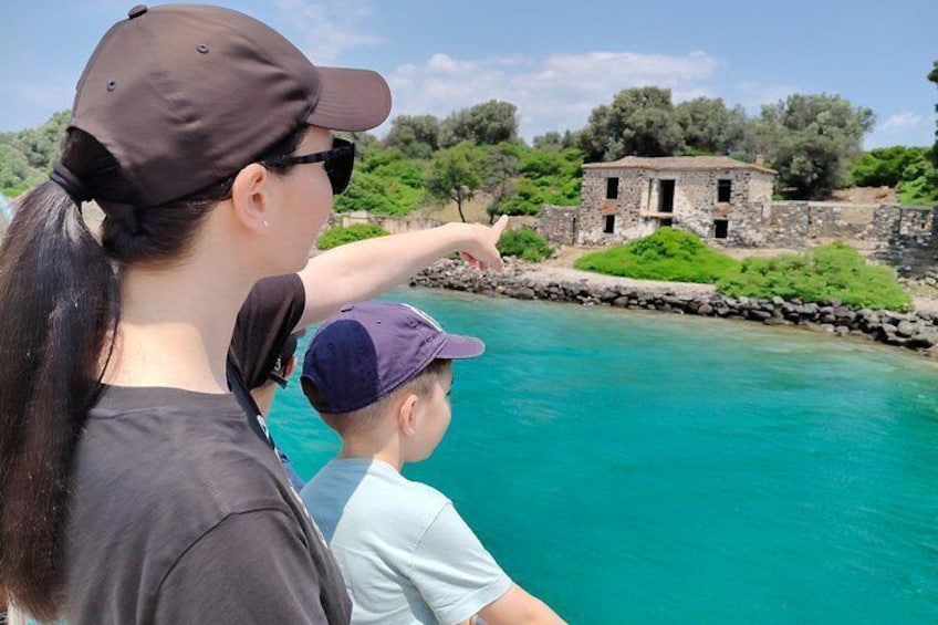 A woman pointing towards a stone building by a turquoise body of water. 4