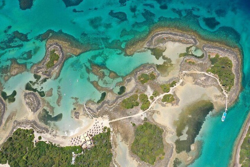 An aerial view of a coastal area with clear turquoise waters, a sandy beach, and a boat dock. 3