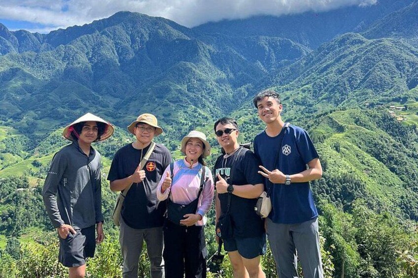 Un grupo de personas sobre una montaña, con abundante vegetación verde y un paisaje montañoso al fondo. 1