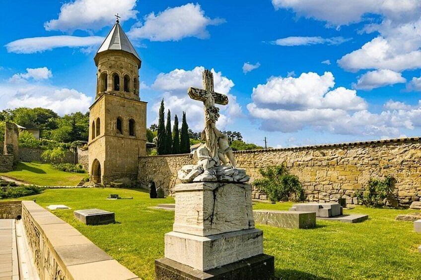 Una iglesia con un campanario, una estatua y un cementerio. 2