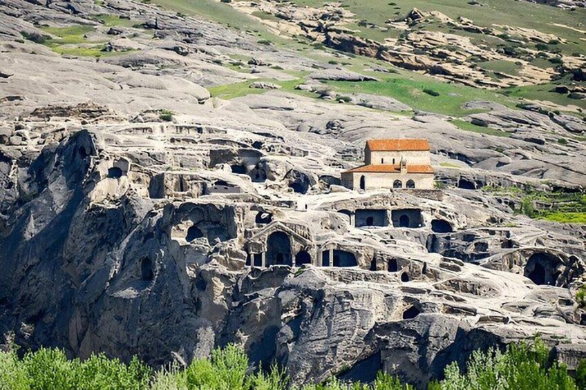 Un paisaje rocoso con ruinas antiguas y un pequeño edificio con techo rojo. 4