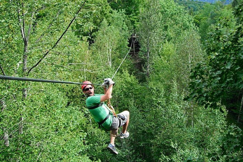Eine Person zipline durch ein bewaldetes Gebiet. 2