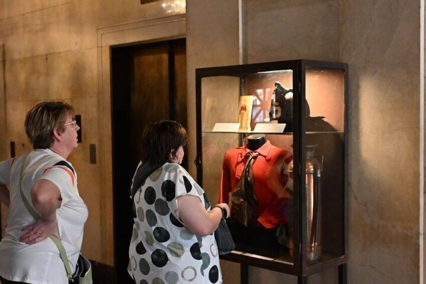 Two people examining a display case with a mannequin and various items inside. 2