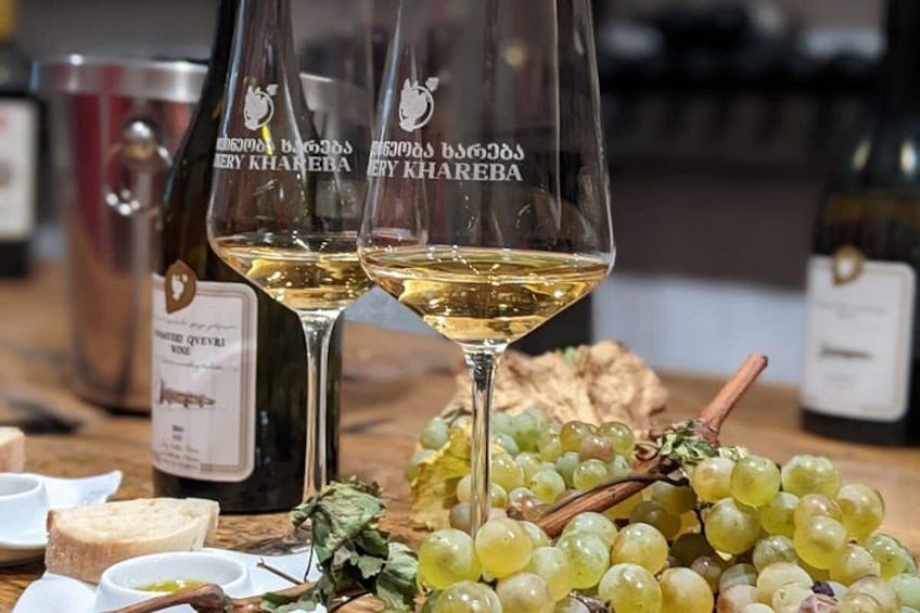 Two wine glasses with a label, a bottle, and a bunch of grapes on a table. 3