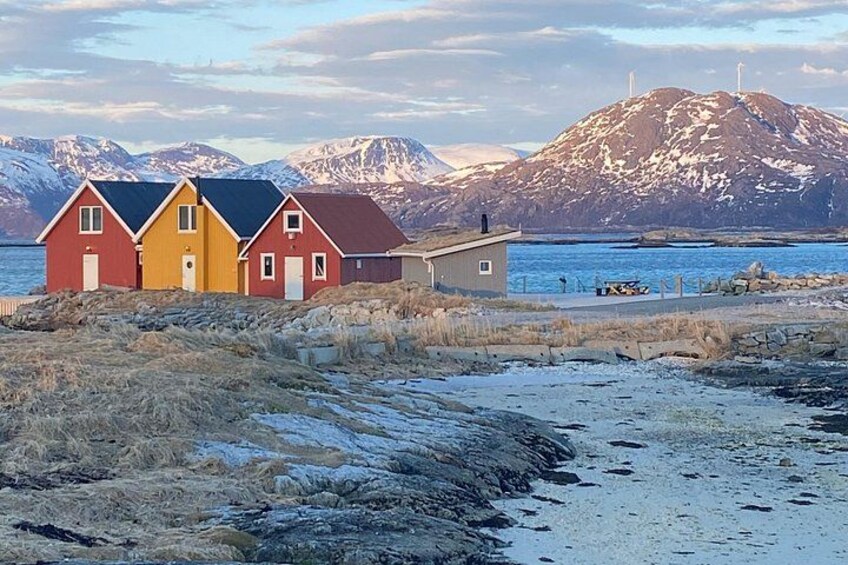 Ett kustlandskap med färgglada hus, en sandstrand och berg i bakgrunden. 1