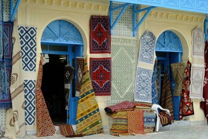 Una tienda con alfombras coloridas exhibidas en el exterior. 2