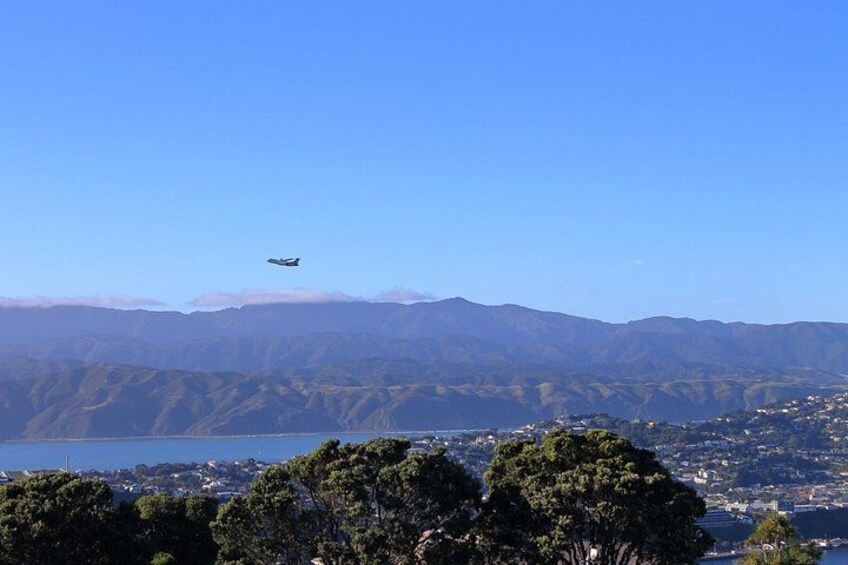 Un avion survole un paysage montagneux, avec un plan d’eau et une ville en contrebas. 5