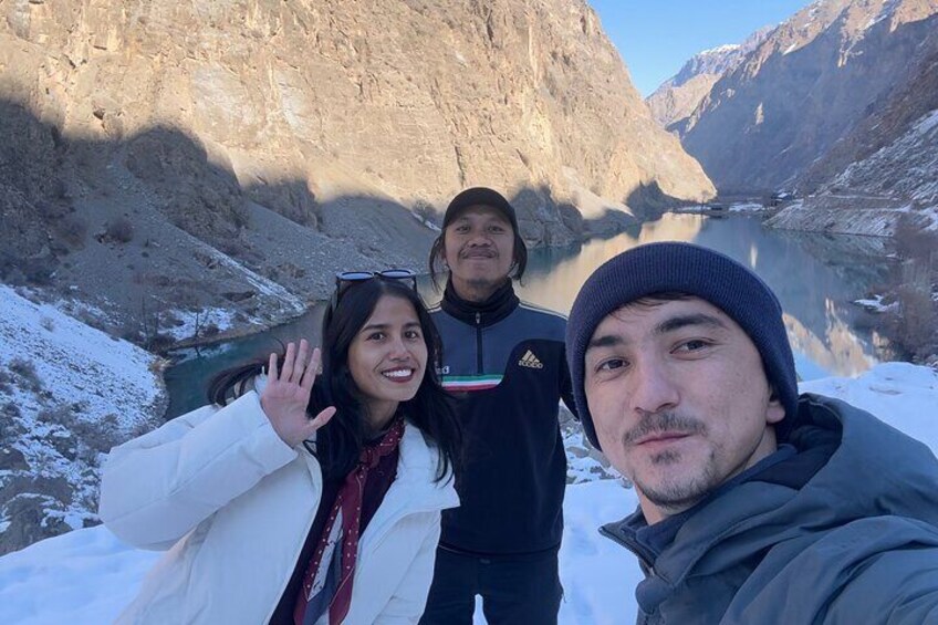 Tres personas en un paisaje nevado de montañas, con un lago al fondo. 1